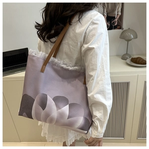 Detalle de bolso tote de lona morada con estampado floral y bordes deshilachados
