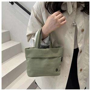 Primer plano del bolso de nailon verde salvia con logo metálico y tejido texturizado