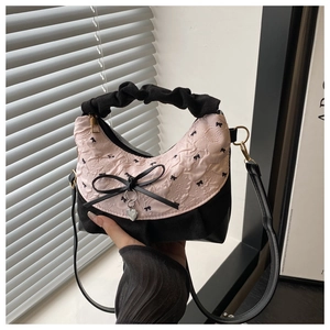 Detail of pink floral bucket bag with black bow and heart pendant on a window ledge