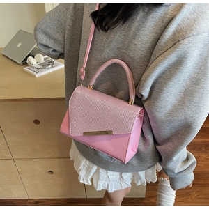 Close-up of pink rhinestone handbag with gold metal bar and adjustable strap