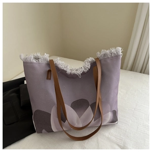 Detalle del bolso tote de lona morada con bordes deshilachados y asas de cuero sintético