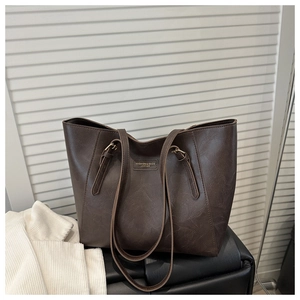 Close-up of vintage brown tote bag with leather texture and metal brand tag details