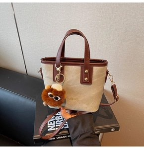 Détail du sac cabas en toile avec garniture en cuir, texte mode et porte-clé peluche