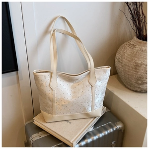 Detail of cream tote bag featuring butterfly floral jacquard and polished PU leather