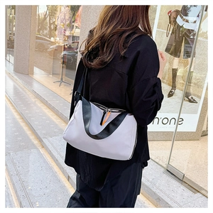 Detailed view of light gray water-repellent nylon crossbody bag with orange accents
