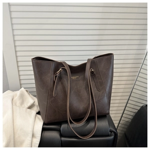 Close-up of brown vintage leather tote bag showing textured finish and logo detail