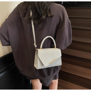 Detail of silver crossbody bag with glitter finish and gold hardware on stairs