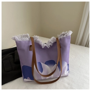 Detalle del bolso de playa en lona violeta con estampado de flores y bordes deshilachados