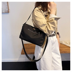 Close-up of black nylon messenger bag with metal zipper and wide shoulder strap detail