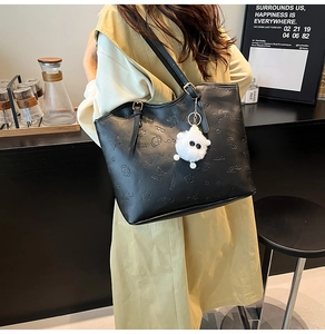 Détail du grand sac cabas noir avec motifs gaufrés et pendentif en peluche décoratif