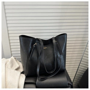 Detailed close-up of a black tote bag with vintage texture and gold adjustable buckle