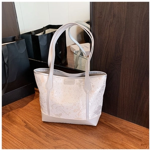 Detail view of large tote bag with floral patterns and a Fashion leather label