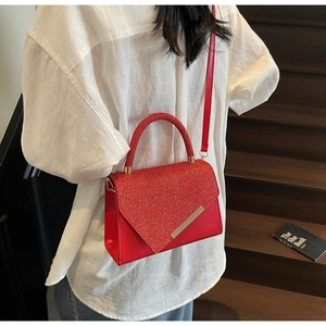 Detail of red glitter crossbody bag with gold trim worn by a model on stairs