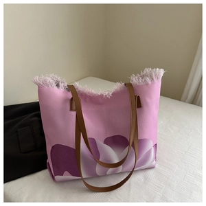 Detalle del bolso tote de lona rosa con bordes deshilachados y estampado de tulipán