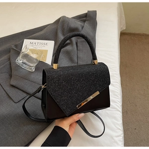 Detail of black mini bag featuring sequined flap and elegant golden metal diagonal bars