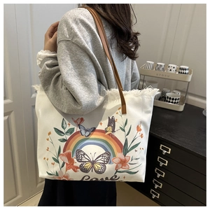 Detail of canvas tote bag with floral rainbow print and frayed edges and leather handle