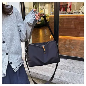 Detail of black nylon shoulder bag with adjustable wide strap and contrast zipper puller