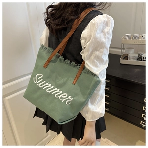 Dettaglio della borsa tote in tela verde con ricamo Summer e bordi sfrangiati sulla spalla
