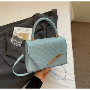 Detail view of light blue handbag featuring triangle geometric texture and gold hardware