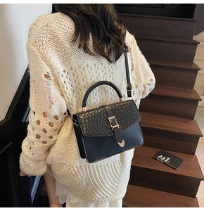 Détail du sac bandoulière noir avec rabat texturé et boucle en métal en forme de cœur