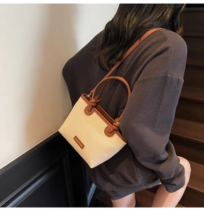 Detail of canvas tote bag with brown leather trim and knotted handle shown on shoulder