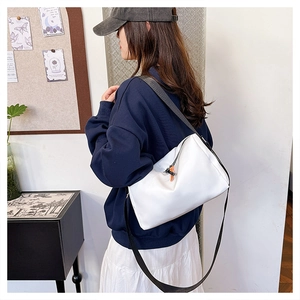 Detail of white nylon crossbody bag with black shoulder strap worn by a model