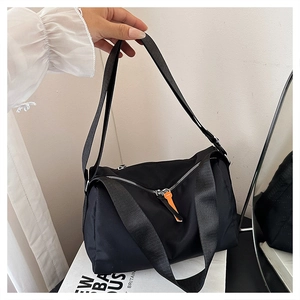 Detailed shot of black nylon shoulder bag with signature orange zipper pulls and dual handles