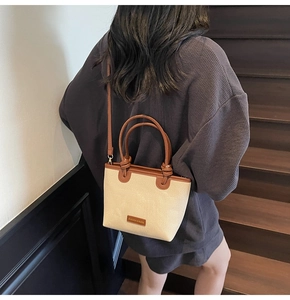 Close-up of canvas bucket bag with brown leather handles on a wooden staircase