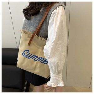 Dettaglio della borsa tote in tela beige con ricamo Summer blu e manici in pelle