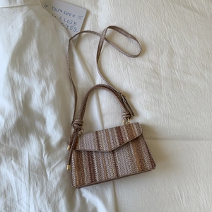 Top view of striped woven crossbody bag with knotted handle and golden hardware details