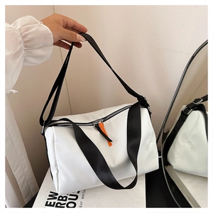 Detail of white cylinder oxford shoulder bag with black strap and orange zipper pulls