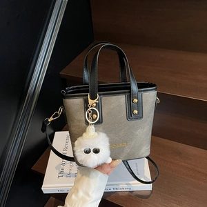 Sac seau en toile grise avec bordure en cuir et charm monstre en peluche blanc