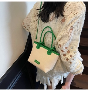 Fashionable off-white canvas bucket bag with green leather trim shown on model
