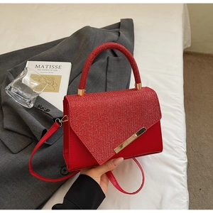 Detail of red sequined handbag with triangular flap and elegant gold metal trim
