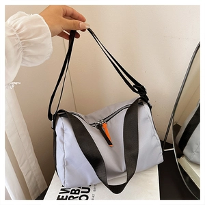 Detail of grey nylon crossbody bag with black straps and bright orange zipper pullers