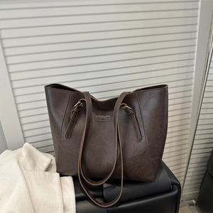 Dark brown faux leather tote bag with long straps on a minimalist interior background