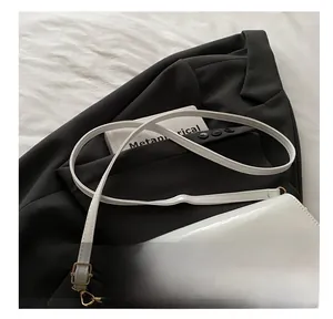 Detail of white glossy square shoulder bag with golden metal buckle and sleek leather strap