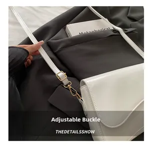 Detail of adjustable golden buckle and glossy white patent leather on the crossbody bag