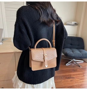 Détail du sac bandoulière en cuir camel avec rabat tissé et boucle en métal doré