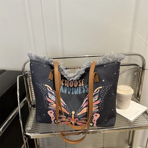 Fashionable canvas tote bag with butterfly print and fringe details on a metal stand