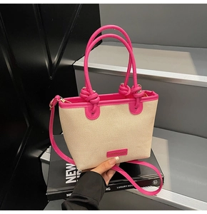 Detail of woven beige bucket bag with pink faux leather straps and knotted handle design