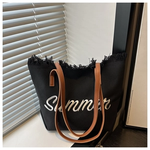 Détail du cabas en toile noire avec broderie Summer et finitions à bords frangés
