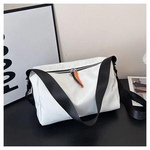 Detail of white nylon crossbody bag featuring wide black strap and orange zipper pull