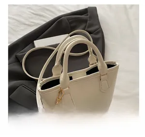 Detail of white leather handbag with metal rings, thin strap and gold logo text
