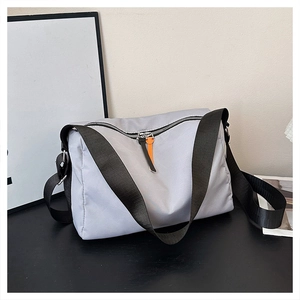 Detail view of light grey nylon messenger bag with black strap and orange zipper puller
