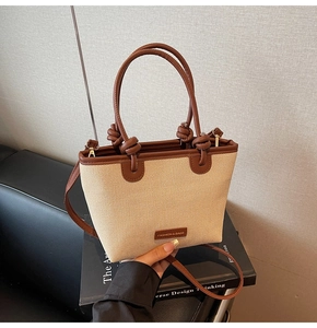 Detail of canvas tote bag with brown leather trim and metal plate branding