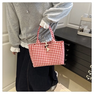 Detail of red gingham canvas tote bag featuring a traditional horn button closure