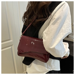 Side view of a vintage wine red patent leather shoulder bag worn by a model