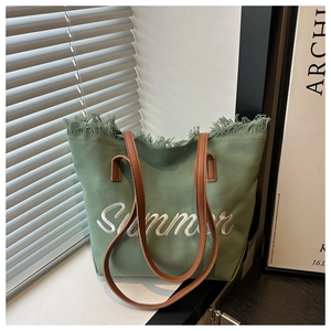 Détail du sac cabas en toile verte avec franges et broderie Summer blanche