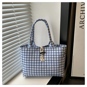 Detail of blue and white checkered canvas tote bag featuring a vintage horn button closure